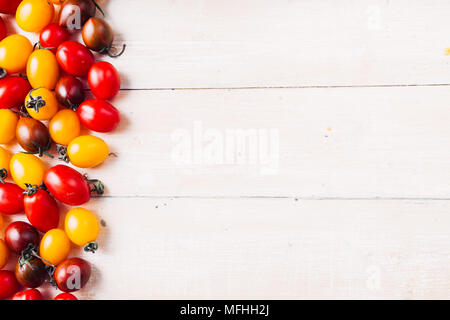 Appena lavato mescolati i pomodori ciliegia dentro uno scolapasta sopra un arrugginito granito sfondo blu Foto Stock