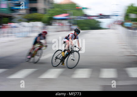 Motion Blur di adolescenti ciclista per competere in una gara amatoriale nel crepuscolo annuale criterium in Atene, GA il 25 aprile 2015. Foto Stock