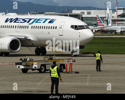 Richmond, British Columbia, Canada. Xvii Apr, 2018. Un WestJet Airlines Boeing 737-700 (C-FWSI) è guidato in posizione sull'asfalto da airport equipaggio a terra. Credito: Bayne Stanley/ZUMA filo/Alamy Live News Foto Stock