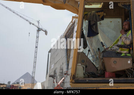 Giza in Egitto. 26 apr, 2018. Un lavoratore edile si trova all interno di un bulldozer presso il cantiere per la costruzione della grande Museo Egizio, backdropped dalla grande piramide di Khufu, in Giza, Egitto, 26 aprile 2018. Credito: Gehad Hamdy/dpa/Alamy Live News Foto Stock