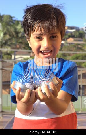 Kid giocando con molla giocattolo. Kid divertirsi giocando con il giocattolo molla elicoidale. Foto Stock