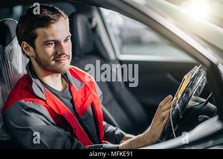 Mechanic seduti in auto esegue la diagnostica sulla tavoletta digitale Foto Stock