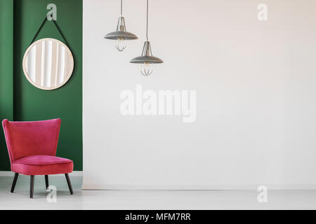 Vita minimalista sala interna con bianco, parete vuota, confortevole sedia retrò e un round specchio appeso in angolo verde Foto Stock