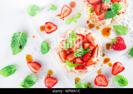 Snack sani con pane fresco Fragole fresche, morbida crema di formaggio, menta, aceto balsamico. Facile colazione close-up su uno sfondo bianco con copia Foto Stock