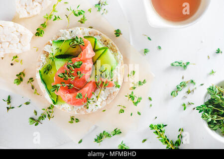 Pane croccante snack sani con salmone, ricotta, strisce di cetriolo, il timo e il pepe. Colazione semplice concetto di close-up con copia spazio. Foto Stock