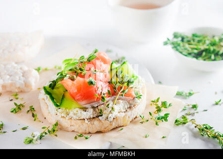 Pane croccante snack sani con salmone, ricotta, strisce di cetriolo, il timo e il pepe. Colazione semplice concetto di close-up con copia spazio. Foto Stock