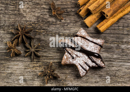 Biscotti allo zenzero con crema di cioccolato su uno sfondo di legno, cannella Foto Stock