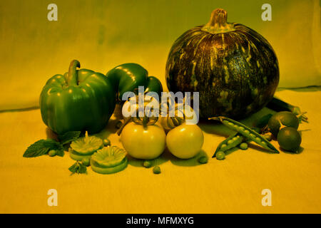 Natura morta con verdura verde : peperoni, pomodori, zucca, piselli, limoni, ladyfinger, foglie di menta e candele. Foto Stock