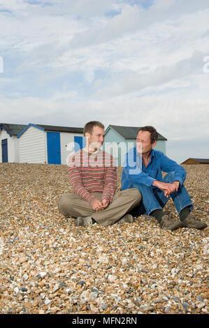 Il giovane e un uomo maturo seduto sulla spiaggia Ref: CRB336 10013 086 Credito obbligatoria: Rob Wilkinson/Photoshot Foto Stock