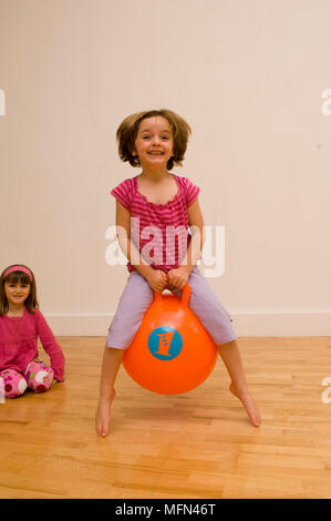 Ritratto di una ragazza che gioca con un pallone gonfiabile e un'altra seduta sul pavimento Ref: obbligatoria credito: Foto Stock