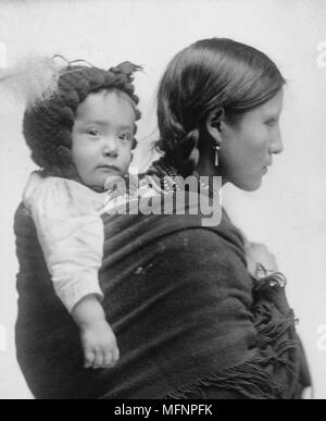 Native American donna dalla regione di pianure, mezza lunghezza verticale, rivolto verso destra con il bambino sulla schiena. Xx secolo ventesimo secolo Foto Stock