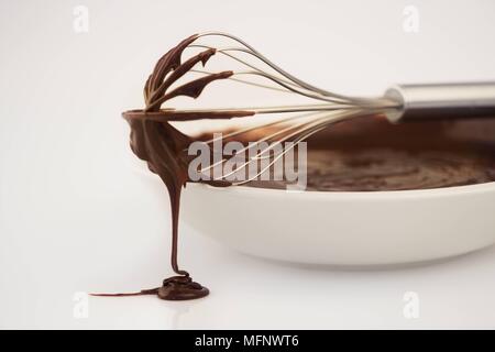 In acciaio inox frusta sul lato della vaschetta di colore bianco con il mix di cioccolato. Sfondo bianco. Studio shot. Ref: CRB538 103609 0023 credito obbligatoria: Marti Foto Stock