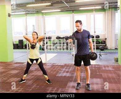 Uomo e donna con kettlebell esercizio in palestra Foto Stock