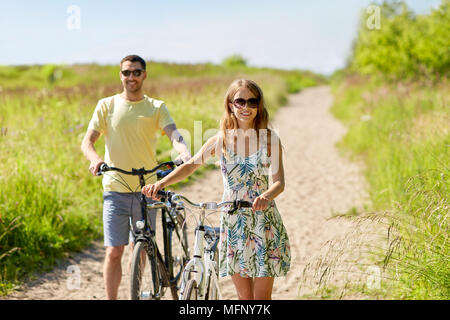 Coppia felice con le biciclette su strada di campagna Foto Stock