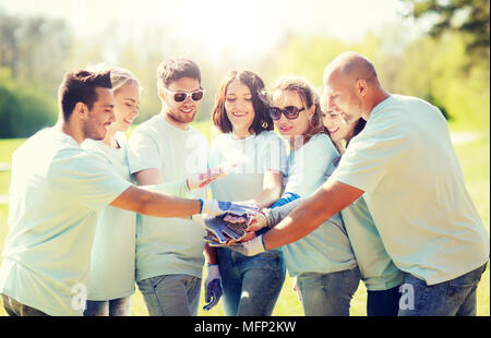 Gruppo di volontari di mettere le mani sulla parte superiore in posizione di parcheggio Foto Stock