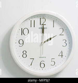 Primo piano della faccia del moderno stile orologio mostra bianco rotondo e quadrante nero al momento due ore su sfondo bianco Foto Stock