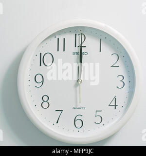 Primo piano della faccia del moderno stile orologio mostra bianco rotondo e quadrante nero al momento dodici ore di mezzogiorno o mezzanotte su sfondo bianco Foto Stock
