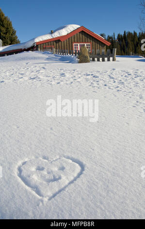 Chalet per le vacanze con la neve e una a forma di cuore smiley tracciata nella neve. Foto Stock