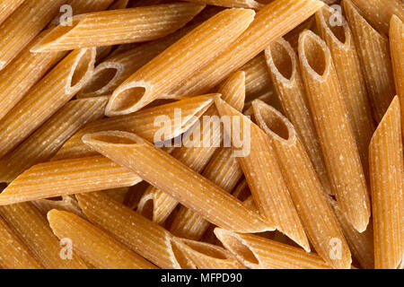 Primo piano di pasta intera di penne di grano non cotte. Immagine di sfondo del cibo. Foto Stock