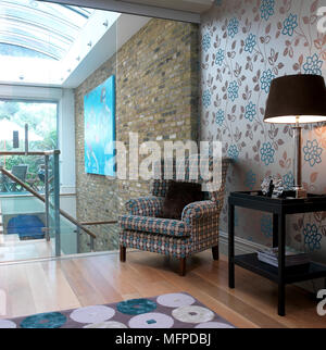 Stile tradizionale wingback imbottiti sedia in un angolo di un livello diviso pavimento in camera contemporanea Foto Stock