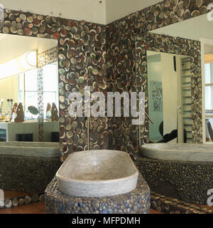 Un abstract di ghiaia e di effetto pietra Bagno con specchio doppio e bagno in marmo impostato in ghiaia e basamento in pietra Foto Stock