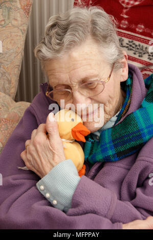 Donna anziana che indossa una giacca di lana e una sciarpa calda in inverno modello di rilascio Foto Stock