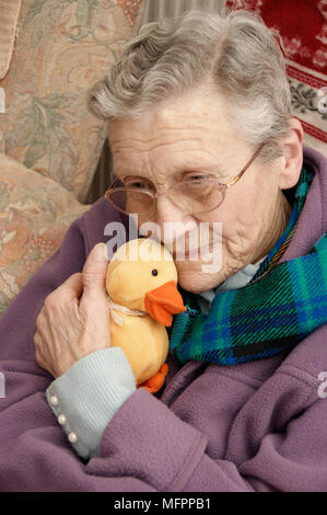 Donna anziana che indossa una giacca di lana e una sciarpa calda in inverno modello di rilascio Foto Stock