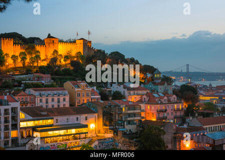 Skyline di Lisbona, vista del Castelo de Sao Jorge illuminato di notte con gli affollati edifici in collina del quartiere Mouraria situato sotto, Portogallo Foto Stock