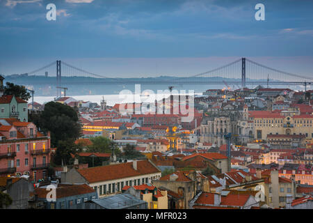 Tramonto a Lisbona, vista al tramonto attraverso i tetti nel centro di Lisbona verso il fiume Tago e il ponte 25 de Abril, Portogallo. Foto Stock