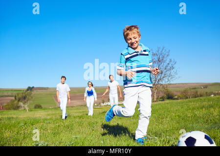 La famiglia felice giocando con una palla sulla natura in primavera, d'estate. Foto Stock