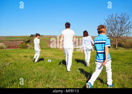 La famiglia felice giocando con una palla sulla natura in primavera, d'estate. Foto Stock