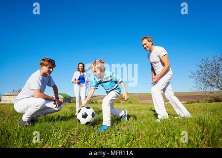 La famiglia felice giocando con una palla sulla natura in primavera, d'estate. Foto Stock