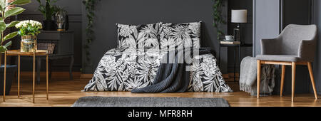 Panorama di scuro, elegante camera da letto interni con coperta grigio sdraiato sul letto con copriletti floreali Foto Stock