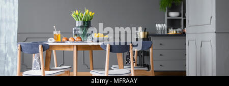 Tulipani gialli sul tavolo da pranzo in legno con sedie in grigio, rustica sala da pranzo interno Foto Stock