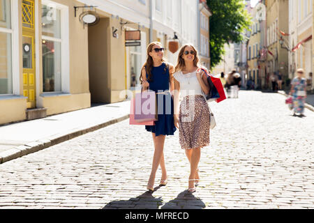 Felici donne con borse per lo shopping passeggiate in città Foto Stock