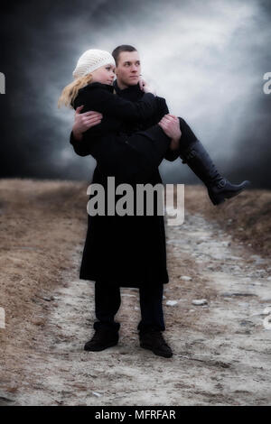 Un uomo porta la sua ragazza su un prato Foto Stock