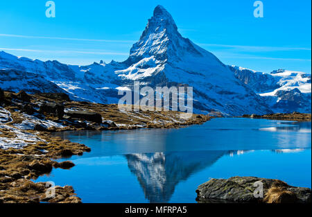 Snowy Matterhorn riflessa nella parzialmente congelato Stellisee, Zermatt, Vallese, Svizzera Foto Stock