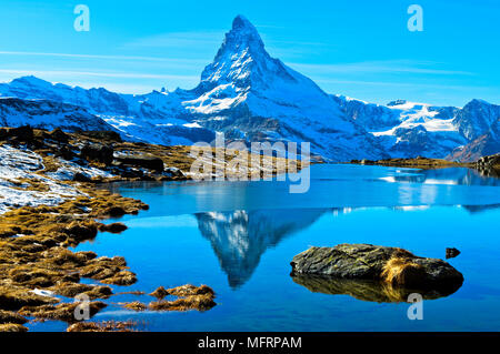 Snowy Matterhorn reflected in the partly frozen Stellisee, Zermatt, Valais, Switzerland Foto Stock