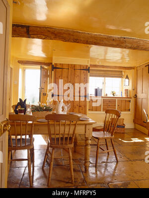 Pine tavolo e sedie nel centro del paese di giallo cucina di stile Foto Stock