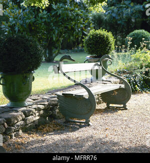 Dettagli giardino con cigno a forma di panca di legno tra le piantatrici di URN. Foto Stock