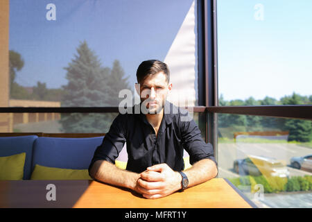 Uomo d'affari americano seduta a office sul divano e indossando la maglia nera. Foto Stock