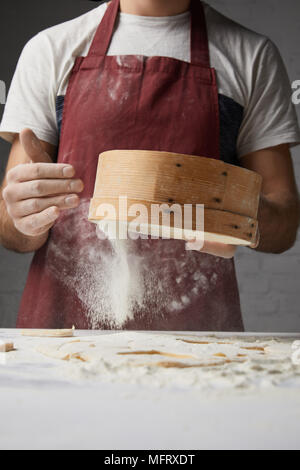 Immagine ritagliata dello chef setacciare la farina con il crivello inferiore Foto Stock