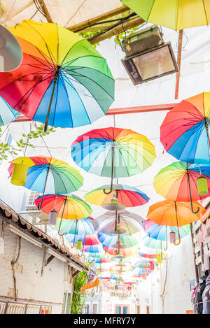 Ombrelloni colorati che pendono a strette strade di Bodrum con case bianche in stile greco Bodrum.La Turchia Foto Stock