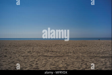 Un paesaggio di un vuoto spiaggia sabbiosa, mostrando un orizzonte con il blu del cielo e del mare con un primo piano di sabbia su una soleggiata giornata calda. Foto Stock