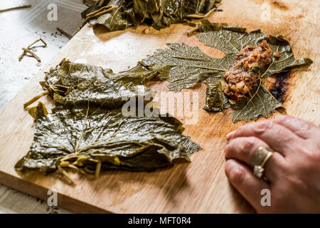 La donna è un involucro di foglie di uva per bagno turco dolma con carne macinata. cibo fatto in casa. Foto Stock