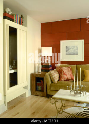 Moderno salotto dettaglio con pavimento di legno, verde oliva divano, rosso tile parete, e built-in media gabinetto. Foto Stock