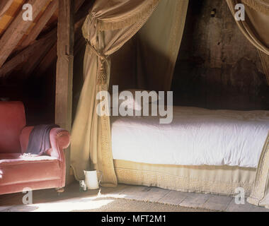 Letto matrimoniale con tende oscuranti accanto alla poltroncina imbottita Foto Stock