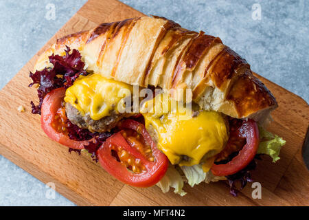Croissant Burger con polpette di carne, formaggio Cheddar e pomodori. Fast Food. Foto Stock