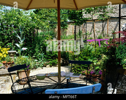 Tavolo e sedie con ombrellone sulla zona patio della città giardino Foto Stock
