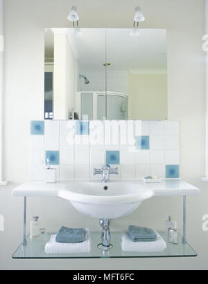 Bagno rivestito di piastrelle con dettaglio montato a parete lavello, ripiano in vetro, piastrelle decorative, e uno specchio. Foto Stock